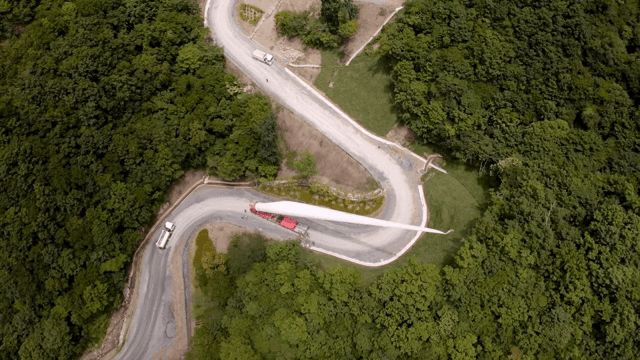 울창한 산 속 구불구불한 도로에서 풍력 터빈 자재를 운반하는 모습