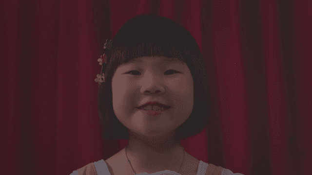 Girl smiling and talking in front of a red curtain