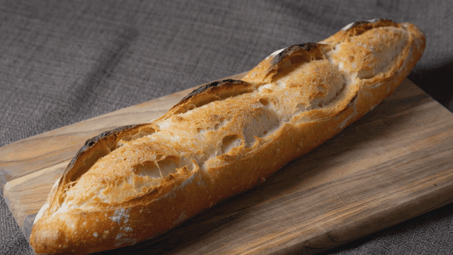 Freshly baked baguette on wooden cutting board