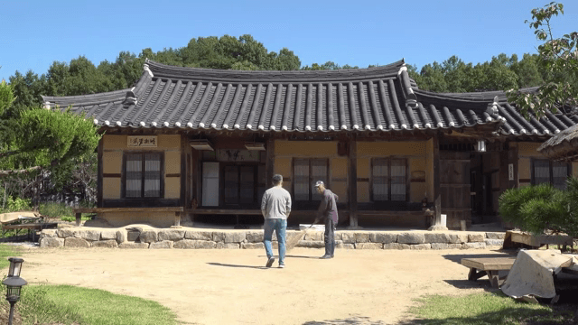 전통 한옥 마당에서 대화를 하는 두 남성