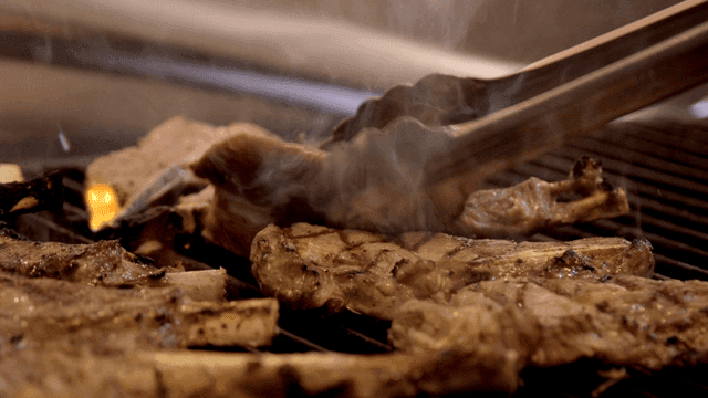 Lamb ribs flipped over with tongs