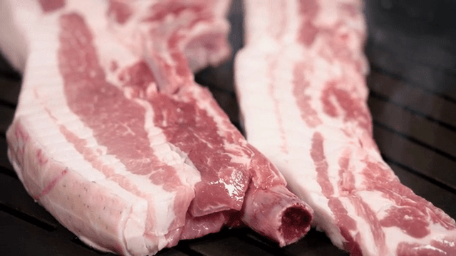 Raw pork belly slices on a grill