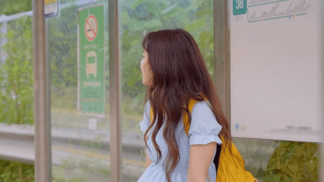 버스 정류장에서 기다리는 젊은 여성