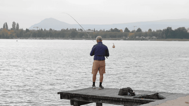 Middle-aged white man fishing from lakeside pier