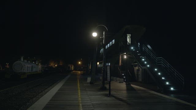 Empty train station platform at night illuminated by street lamps