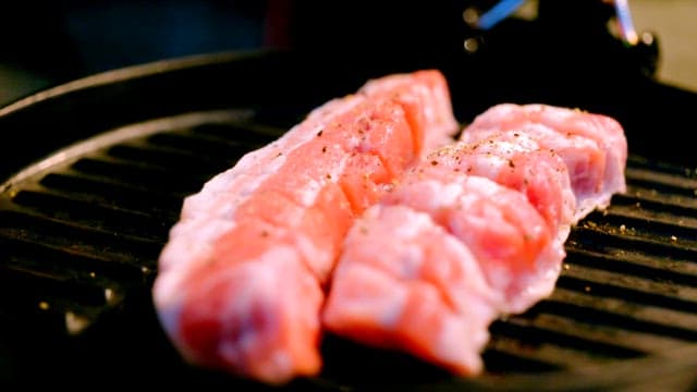 Seasoned pork grilling on a hot pan