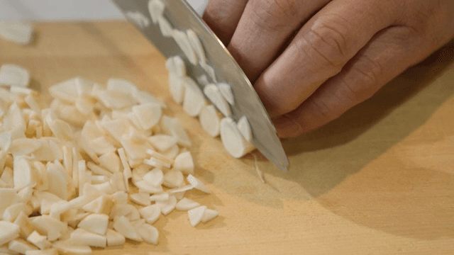나무 도마 위에서 마늘을 써는 모습
