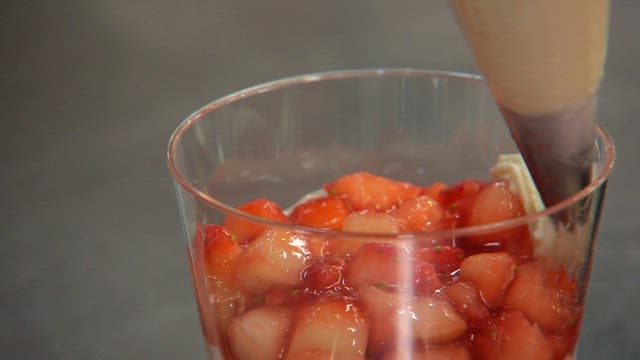 Whipped cream being piped onto strawberries