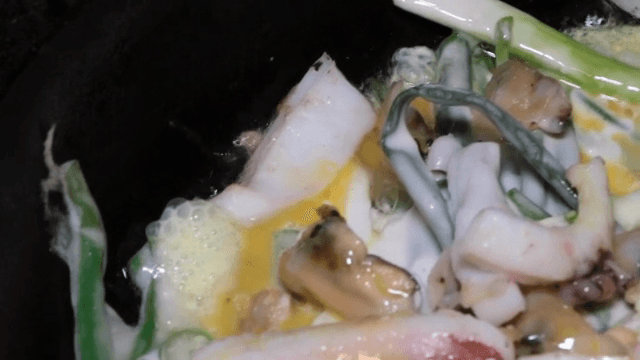 팬에서 요리 중인 해산물과 채소가 들어간 전