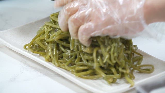 Stir-fried sweet potato stem in sesame oil, plated on a plate on the table