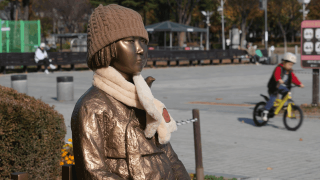 사람들이 지나가는 공원의 겨울에 소녀상