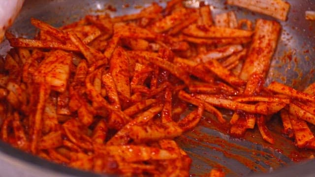 큰 그릇에서 고춧가루를 섞어 무생채 만들기