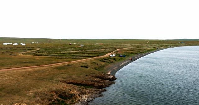 Serene lakeside with distant yurts