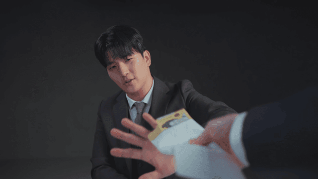 정장을 입은 남자가 돈 봉투를 거절하는 장면