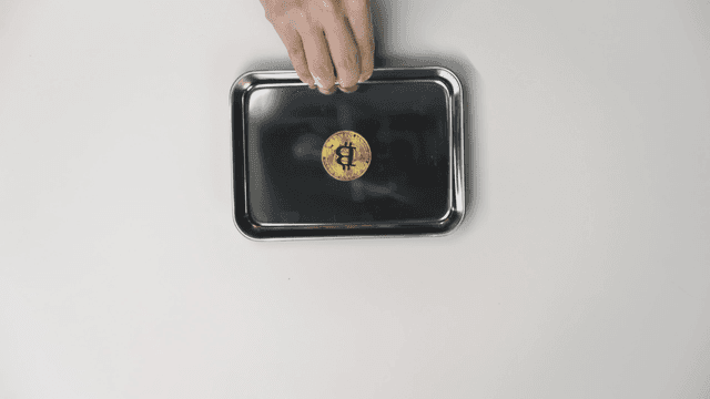 Hand offering a tray with a Bitcoin on it
