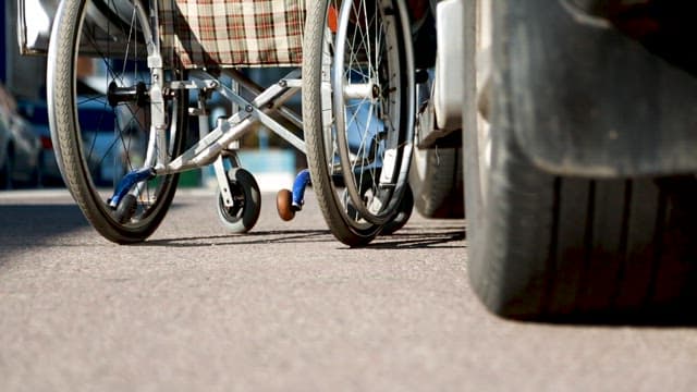 휠체어를 끌고 골목길을 나서는 사람