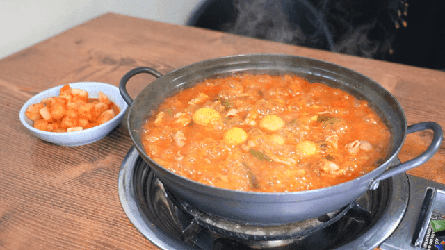 Spicy chicken offal stew boiling in pot with open lid