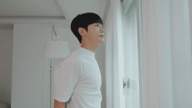 밝은 거실의 창가에 서서 스트레칭하는 남자