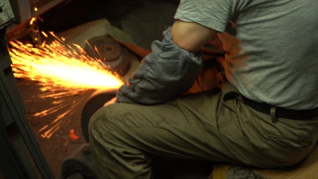 Worker sharpening a knife with sparks