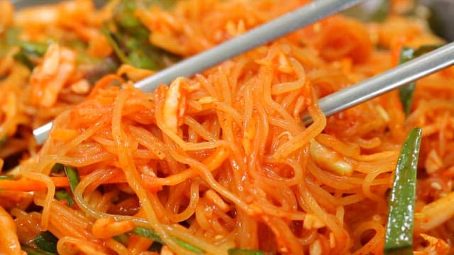 Chopstickful of delicious bibim jjolmyeon with fresh vegetables