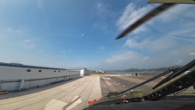 View from helicopter cockpit above runway on a clear day