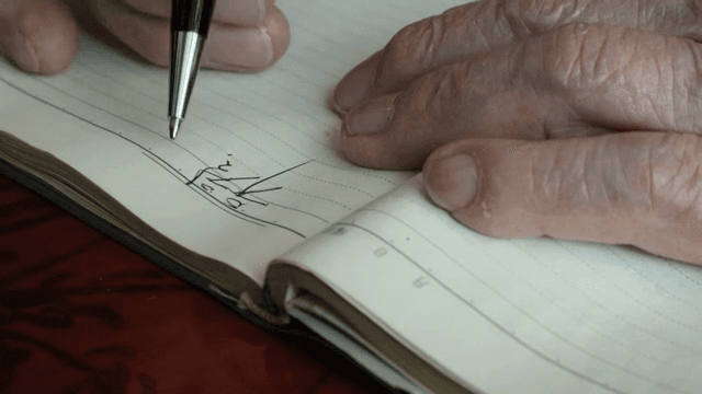 An elderly person writing in a notebook