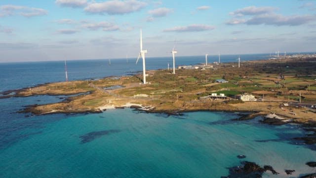 Emerald coastal landscape with wind turbines under a bright sky