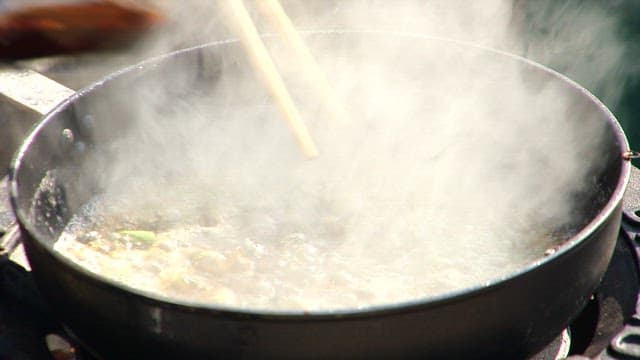 Pouring the soy sauce into the frying pan that is being cooked