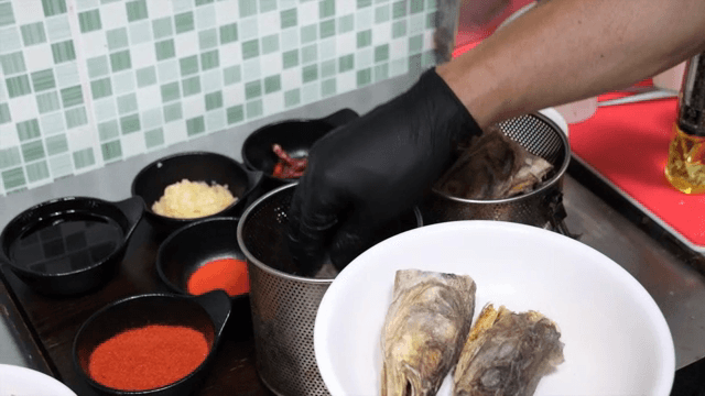 Scene of putting fish heads into a metal container