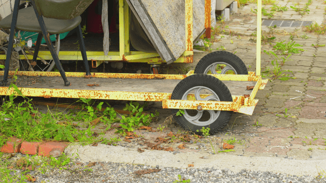Rusty cart wheel with overgrown weeds