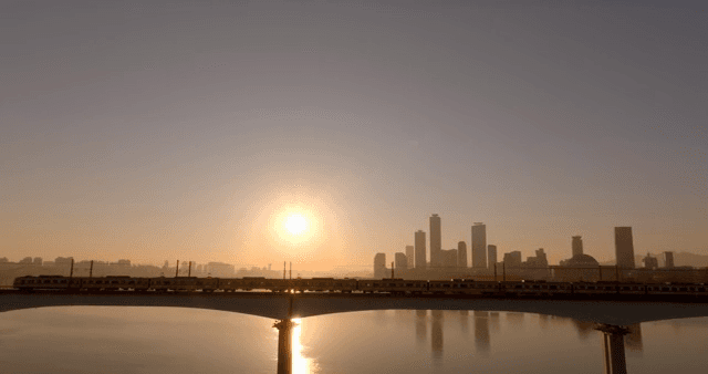 Train crossing a bridge over a river at sunset