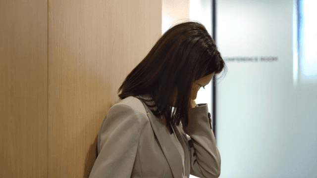 벽에 기대어 있는 피곤한 정장 입은 여성