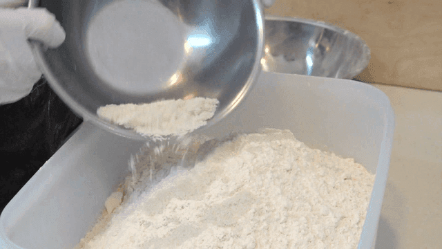 밀가루가 담긴 큰 용기에 섬세하게 부워지는 소금