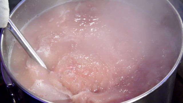 Boiling meat in a pot with steam rising