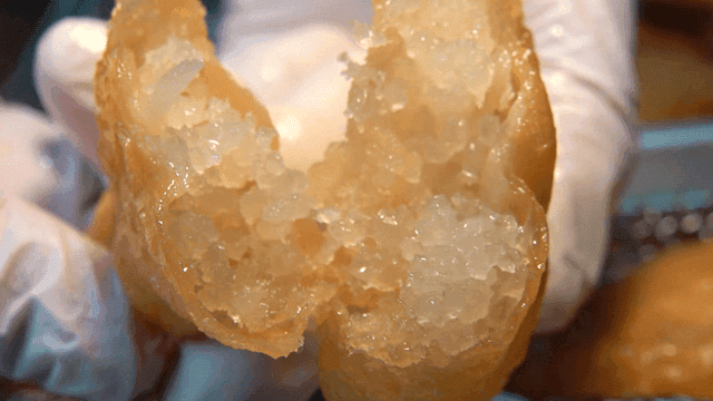 튀긴 만두를 반으로 가르는 장갑 낀 손