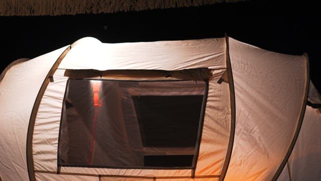 Setting up a tent at night in an outdoor camping site.