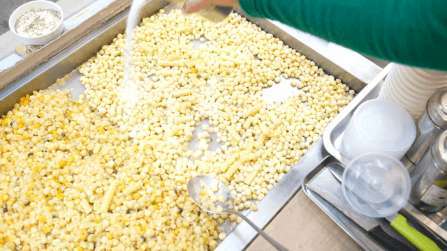 Corn being seasoned with salt