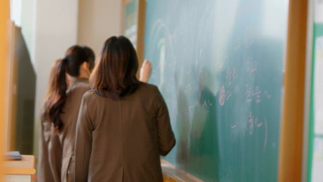 Students scribbling on a classroom blackboard