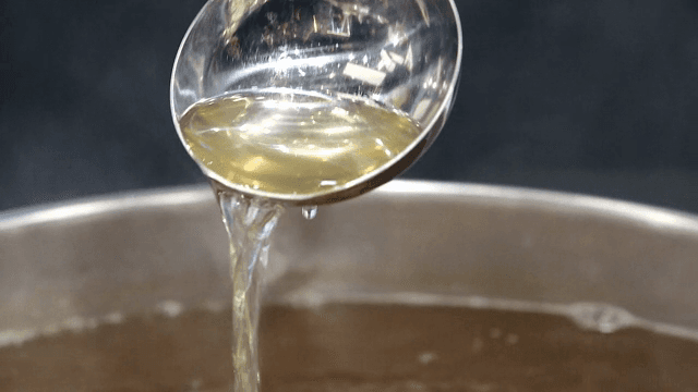 Ladle pouring broth into a pot