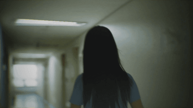 Back of woman walking down dark hallway