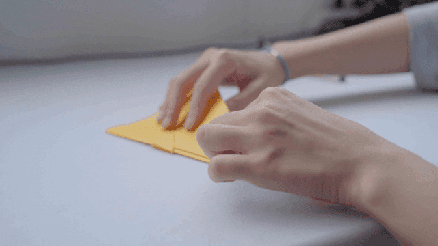 책상 위에서 노란 종이를 접는 손