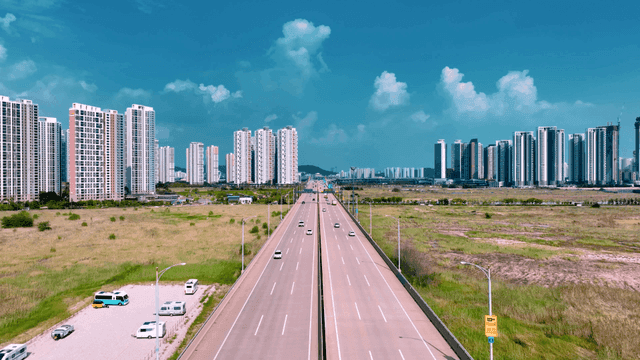 Highway leading to city with high-rise buildings.