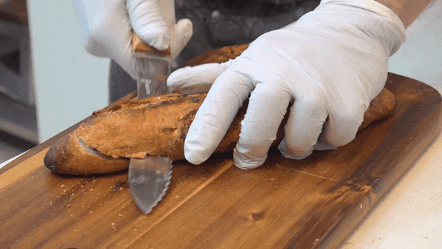 Fresh baguette cut in half on cutting board