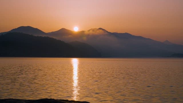 Sunrise Over a Lake Under Tranquil and Misty Mountain