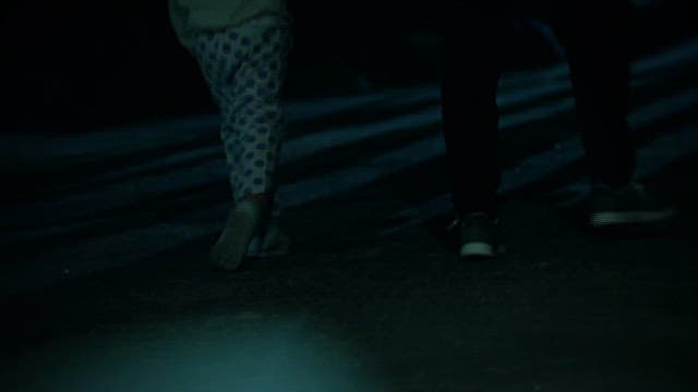 Person Walking Down the Street at Night Holding a Child's Hand