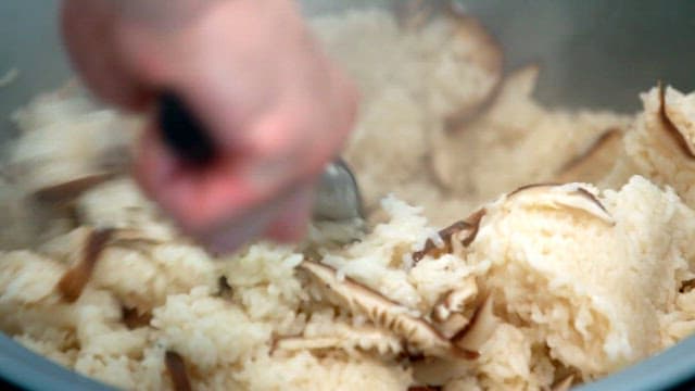 김이 모락모락 나는 표고버섯이 들어간 밥을 주걱으로 젓는 모습