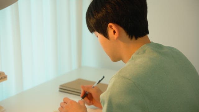 Man writing at a desk in a calmly lit room