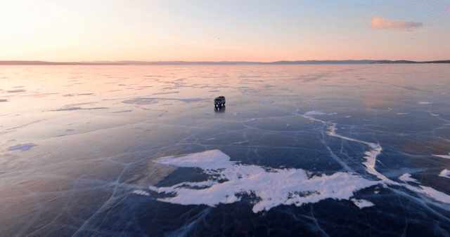 해질녘 얼어붙은 호수 위를 달리는 차량