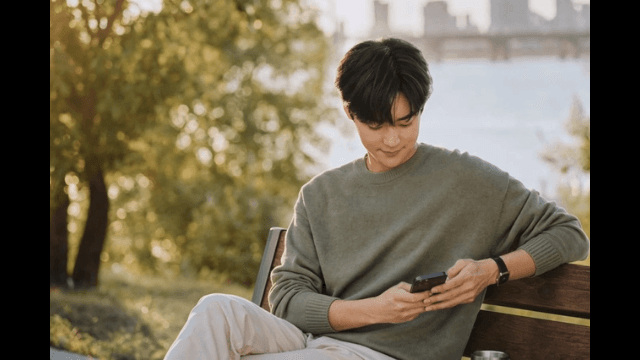 Man sitting on park bench looking at his phone