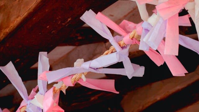 전통 가옥의 새끼줄에 소원을 적은 종이를 묶는 사람